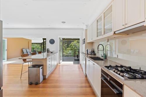 a kitchen with white cabinets and a hardwood floor at Poolside oasis - Sydney in Sydney