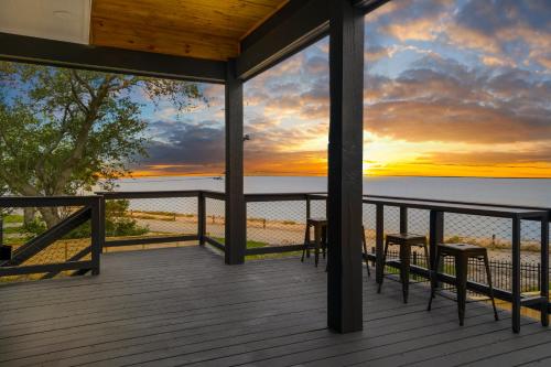 a deck with two chairs and a sunset at Waterfront Home with Views - Hot Tub & Movie Theatre in Bacliff