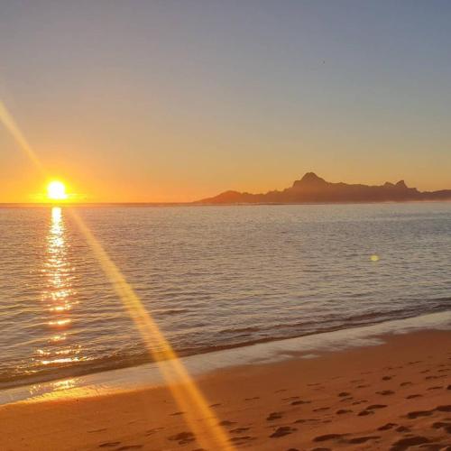 a sunset on the beach with the sun setting at TAHITI - Fare Vainato Beach in Punaauia