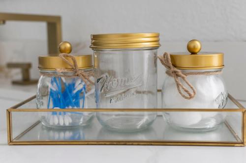 three glass jars with gold tops on a glass shelf at Chic 4BR Home Hot Tub Game Room in Port Saint Lucie