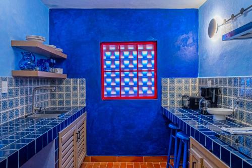 a blue kitchen with blue walls and a red window at Casona Quetzal in Guadalajara