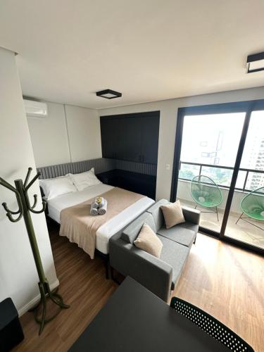 a bedroom with a bed and a couch and a window at Studio Cuiabá NOVO - Frente ao Shopping Estação in Cuiabá