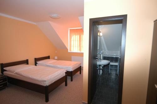 a room with two beds and a bathroom with a sink at Toscca in Čelákovice