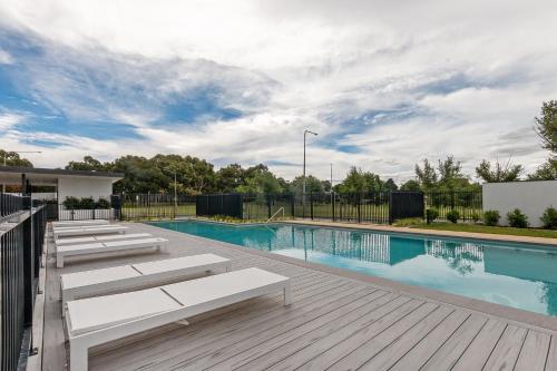 une piscine avec des bancs à côté d'une terrasse en bois dans l'établissement Cosy 1-Bed with Pool, Gym and Secure Parking, à Phillip