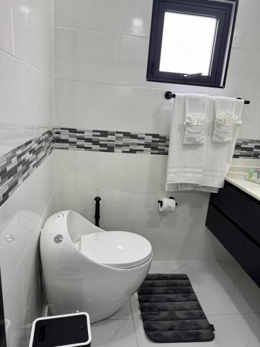 a white bathroom with a toilet and a window at Tranquility Love Bay in Richmond