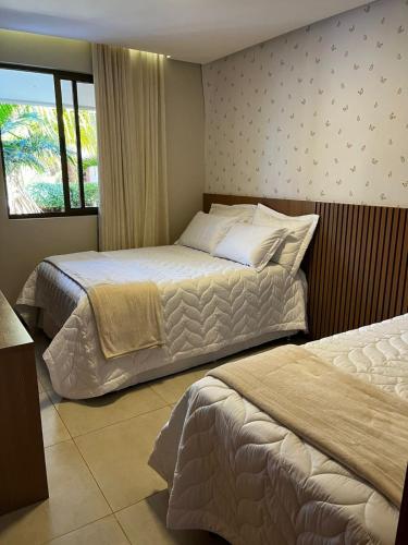 ein Hotelzimmer mit zwei Betten und einem Fenster in der Unterkunft Village Itacimirim Boulevard - Pé na areia in Itacimirim