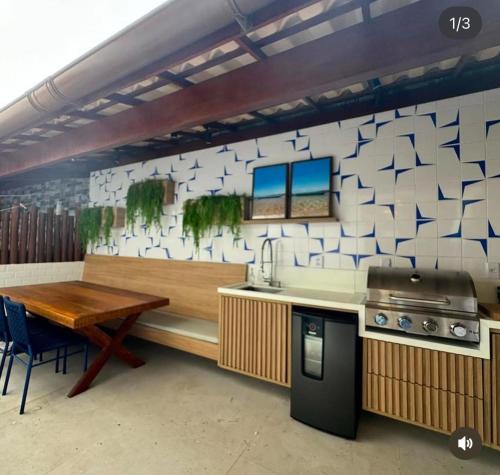 eine Küche mit einer Theke, einem Tisch und einer Arbeitsplatte in der Unterkunft Village Itacimirim Boulevard - Pé na areia in Itacimirim