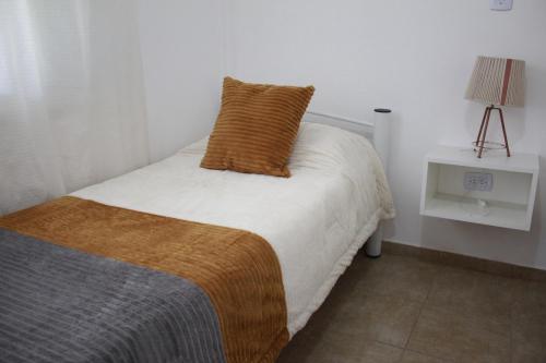 a bedroom with a bed with a brown pillow on it at Pueblo Dorado in Malargüe