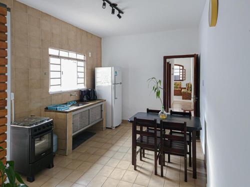 a kitchen with a table and a white refrigerator at Casa Térrea Pet Friendly 8 Pessoas Ubatuba in Ubatuba