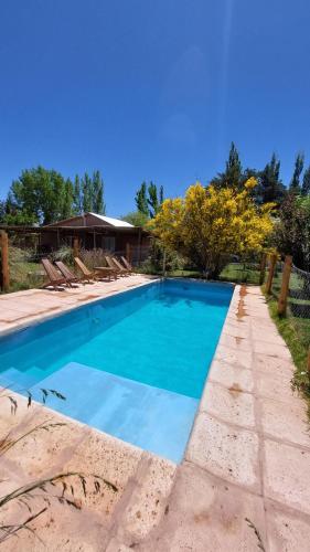 een blauw zwembad met stoelen en een huis bij Cabañas EL AGUARIBAY in Barreal