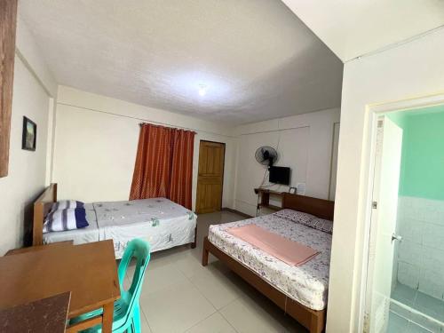 a bedroom with two beds and a desk and a window at JEMZ Tagaytay Budget Transient in Kaybagal