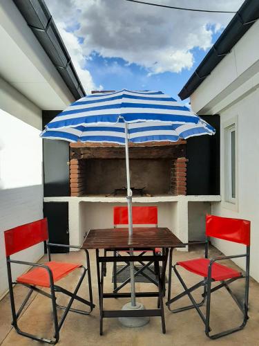 a table with a blue and white umbrella and red chairs at Pueblo Dorado in Malargüe