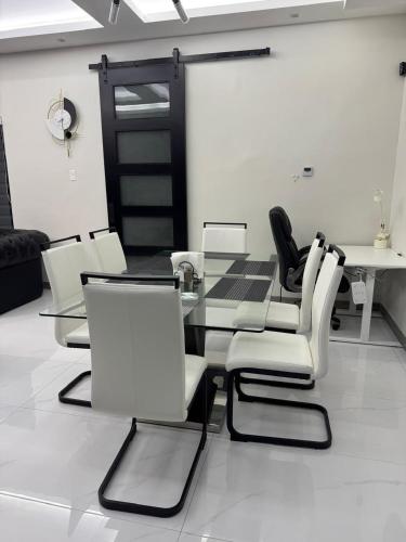 a dining room with a glass table and white chairs at Tranquility Love Bay in Richmond