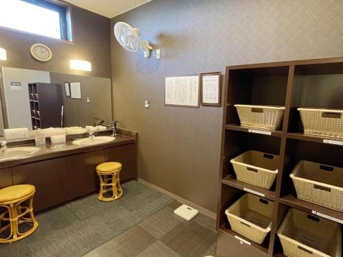 a bathroom with a sink and a mirror and two stools at Hotel Route-Inn Dai-ni Ashikaga in Ashikaga