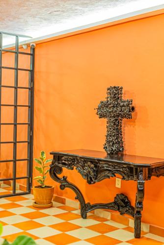 a cross on a orange wall next to a table at Casona Quetzal in Guadalajara