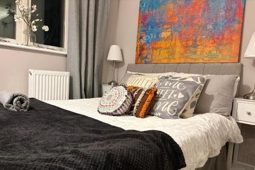 ein Schlafzimmer mit einem Bett mit Kissen und einem Gemälde in der Unterkunft Beautiful Rooms near Hampton Court in Molesey