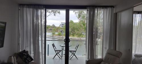 a living room with a large window with a table and chairs at Marina View Apartment on the Maribyrnong River, Melbourne in Maribyrnong