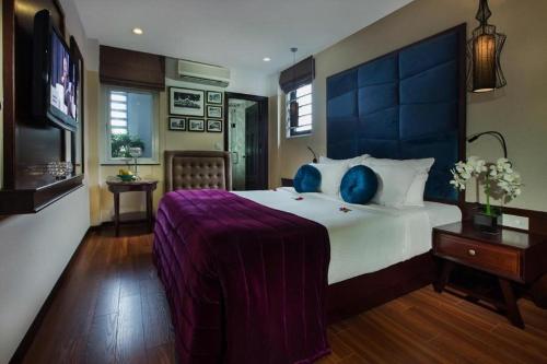 a bedroom with a large bed with a purple blanket at Ambassador Hanoi Hotel & Spa in Hanoi