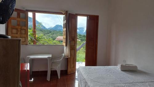 a bedroom with a bed and a table and a window at Pousada Serra Aquarela in Ibicoara
