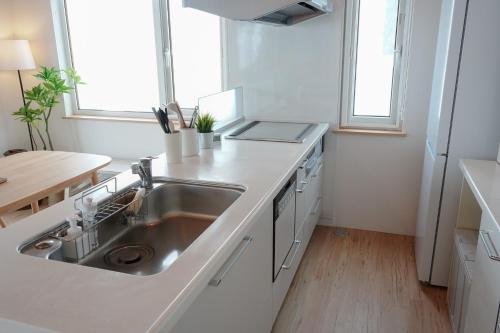 a white kitchen with a sink and a table at Niseko Hulk18 in Niseko