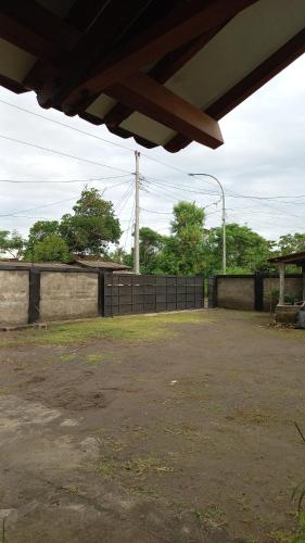 an empty parking lot with a fence and trees at Niti Guest House in Tegalan