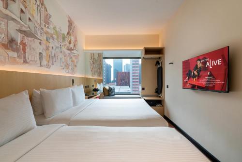 a hotel room with two beds and a movie poster on the wall at Ibis Singapore on Bencoolen - Newly Renovated in Singapore