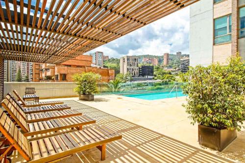 une terrasse avec bancs en bois et une piscine dans l'établissement Amazing 3 bedroom near Provenza- El Poblado 701, à Medellín