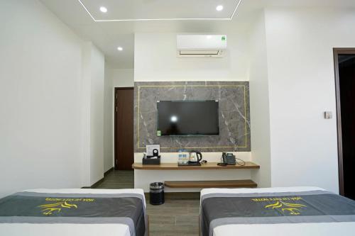 a room with two beds and a tv on the wall at Hoa Lư City Hotel in Ninh Binh