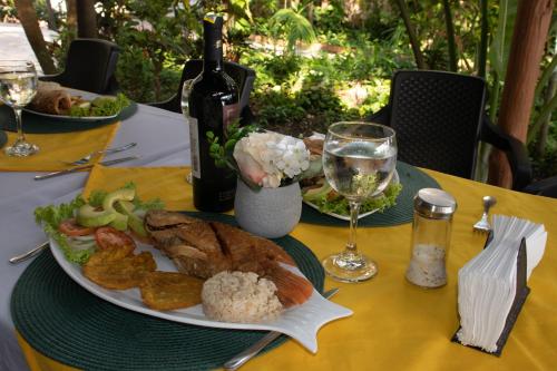 a table with a plate of food and a bottle of wine at Hotel Isla Real in Tierra Bomba