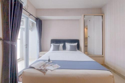 a large bed in a room with a window at Cozy Living Studio at Paramount Skyline Apartment By Travelio in Tangerang
