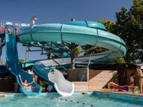 - un toboggan bleu dans une piscine avec un bateau dans l'établissement Chalet de Luxe au Calme avec Piscines Chauffées, Clim et Prestations Haut de Gamme - FR-1-778-24, à Saint-Georges-dʼOléron