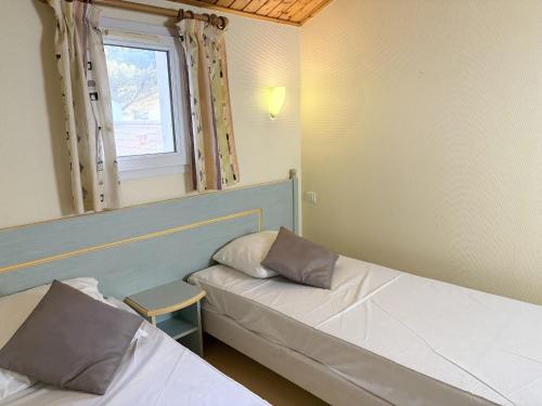 une petite chambre avec deux lits et une fenêtre dans l'établissement Maison de vacances 2 chambres avec jardin, terrasse ensoleillée et parking, au calme et boisée - FR-1-323-541, à Saint-Jean-de-Monts