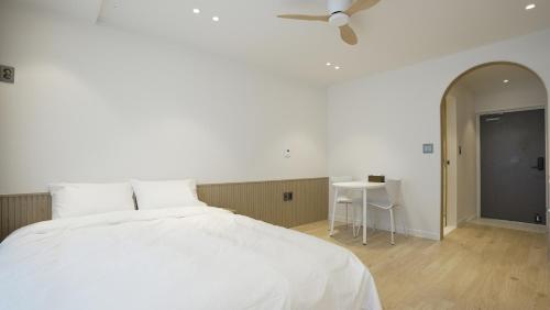 a bedroom with a white bed and a table at Stay Yongdam in Jeju