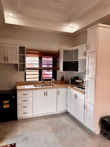a kitchen with white cabinets and a sink at Beachscape At Black River Ethlyn by the sea in Black River