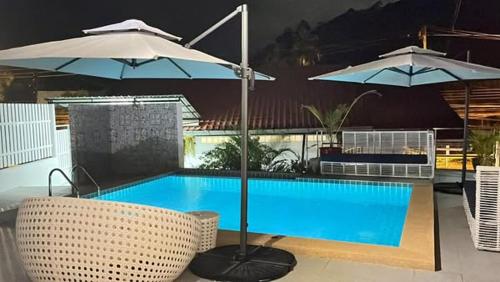 a swimming pool with two umbrellas and two chairs at Elephant Sports Bar and Accommodation in Phuket