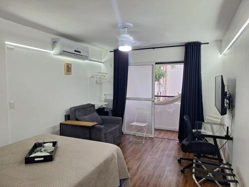 a living room with a table and a chair and a couch at Studio tipuana, varandinha aberta com rede in Brasilia