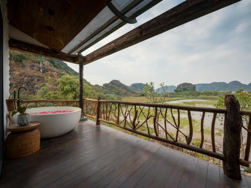 a bathroom with a tub on a deck with a view at Ailee Villa&Hotel TamCoc in Ninh Binh