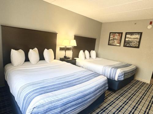 a hotel room with two beds with white pillows at AmericInn by Wyndham Ames in Ames