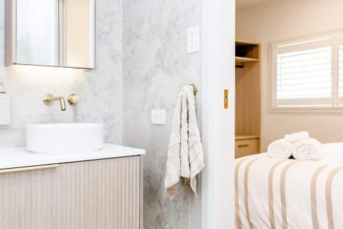 a white bathroom with a sink and a bed at The Lookout in Bargara