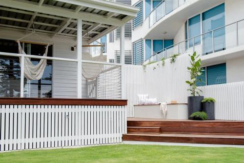 a white fence with a wooden bench in front of a building at The Lookout in Bargara