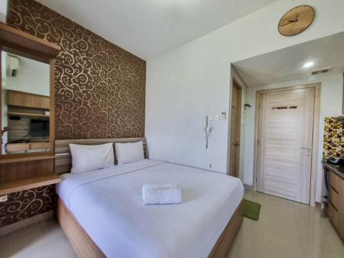 KejayanにあるModern Look Studio at Taman Melati Sinduadi Apartment By Travelioのベッドルーム1室(大きな白いベッド1台、壁に時計付)