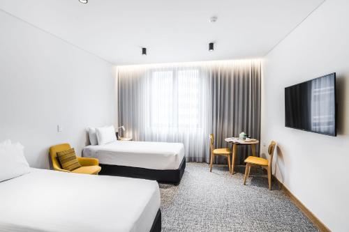 a hotel room with two beds and a tv at Mary MacKillop Place in Sydney
