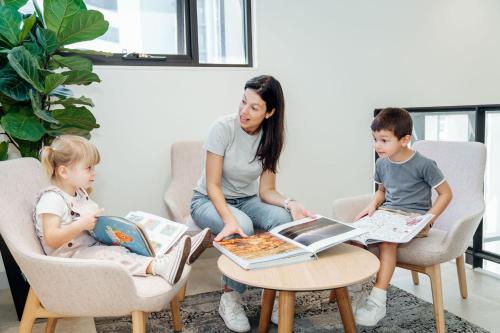 a woman and two children sitting around a table with pizza at Mary MacKillop Place in Sydney