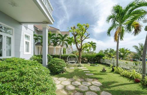 a yard with palm trees and a white house at Villa Sea Links ( Biệt Thự nghỉ dưỡng ) in Ấp Phú Tịnh (2)