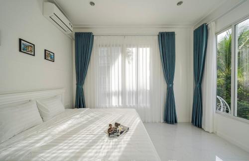 a bedroom with a large white bed with blue curtains at Villa Sea Links ( Biệt Thự nghỉ dưỡng ) in Ấp Phú Tịnh (2)