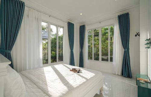 a bedroom with a bed with blue curtains and windows at Villa Sea Links ( Biệt Thự nghỉ dưỡng ) in Ấp Phú Tịnh (2)