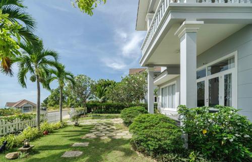 a white house with a garden and palm trees at Villa Sea Links ( Biệt Thự nghỉ dưỡng ) in Ấp Phú Tịnh (2)