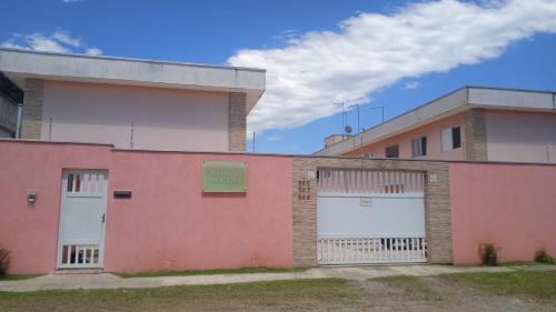 ein rosafarbenes Gebäude mit zwei weißen Garagentüren in der Unterkunft Boracéia Appartamento garaje & funcionalidade in Bertioga