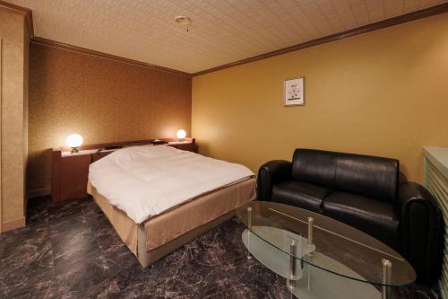 a hotel room with a bed and a couch at ホテルレスポアール in Minatomachi