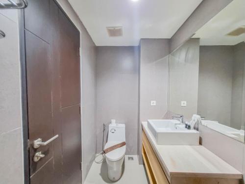 a bathroom with a sink and a toilet at Homey and Minimalist Studio at Patraland Amarta Apartment By Travelio in Kejayan